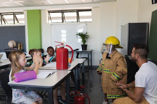 Child dressed as firefighter in classroom demonstration.