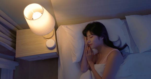 Closeup top view asian woman lying on bed using white noise machine helping sleeping quality at night