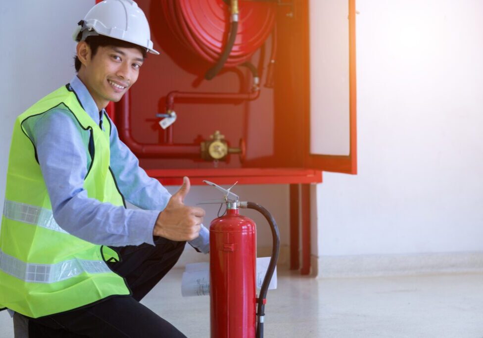 Man in safety gear with fire extinguisher.