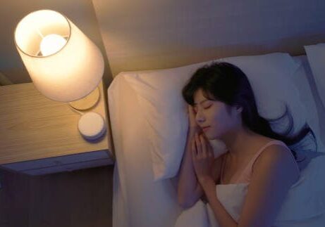 Closeup top view asian woman lying on bed using white noise machine helping sleeping quality at night